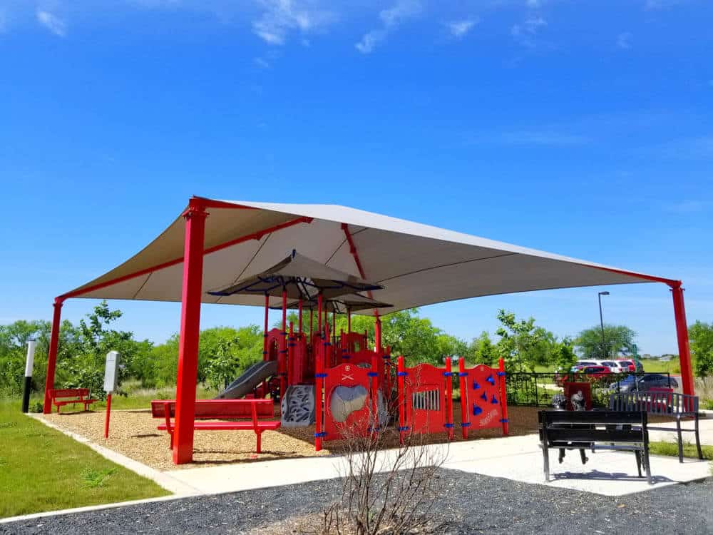 Alt Text: Hip shade structure installed over a playground in Austin, Texas, providing sun protection and comfort for outdoor recreation areas.